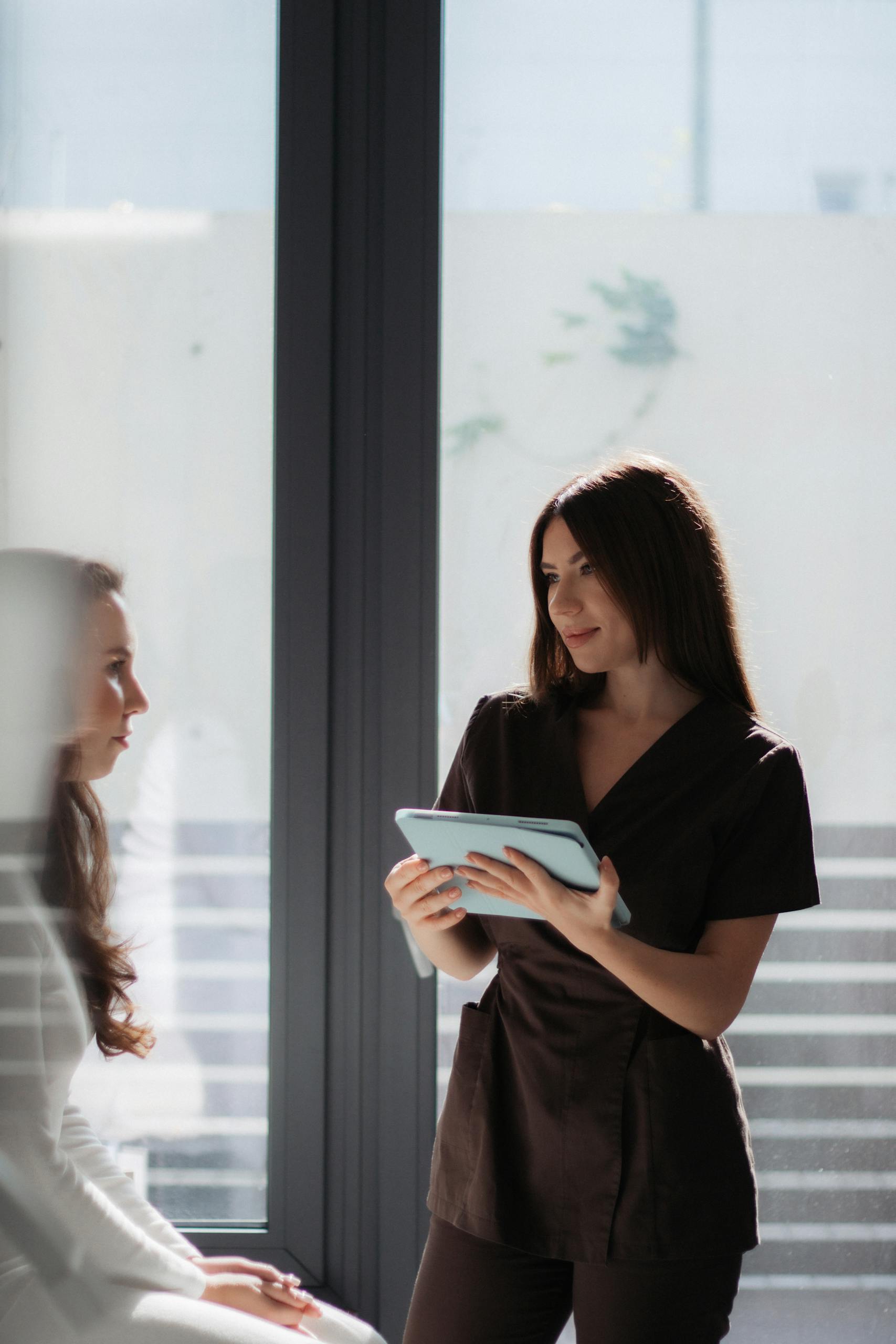 A healthcare professional consults with a patient using a digital tablet in a well-lit clinic.